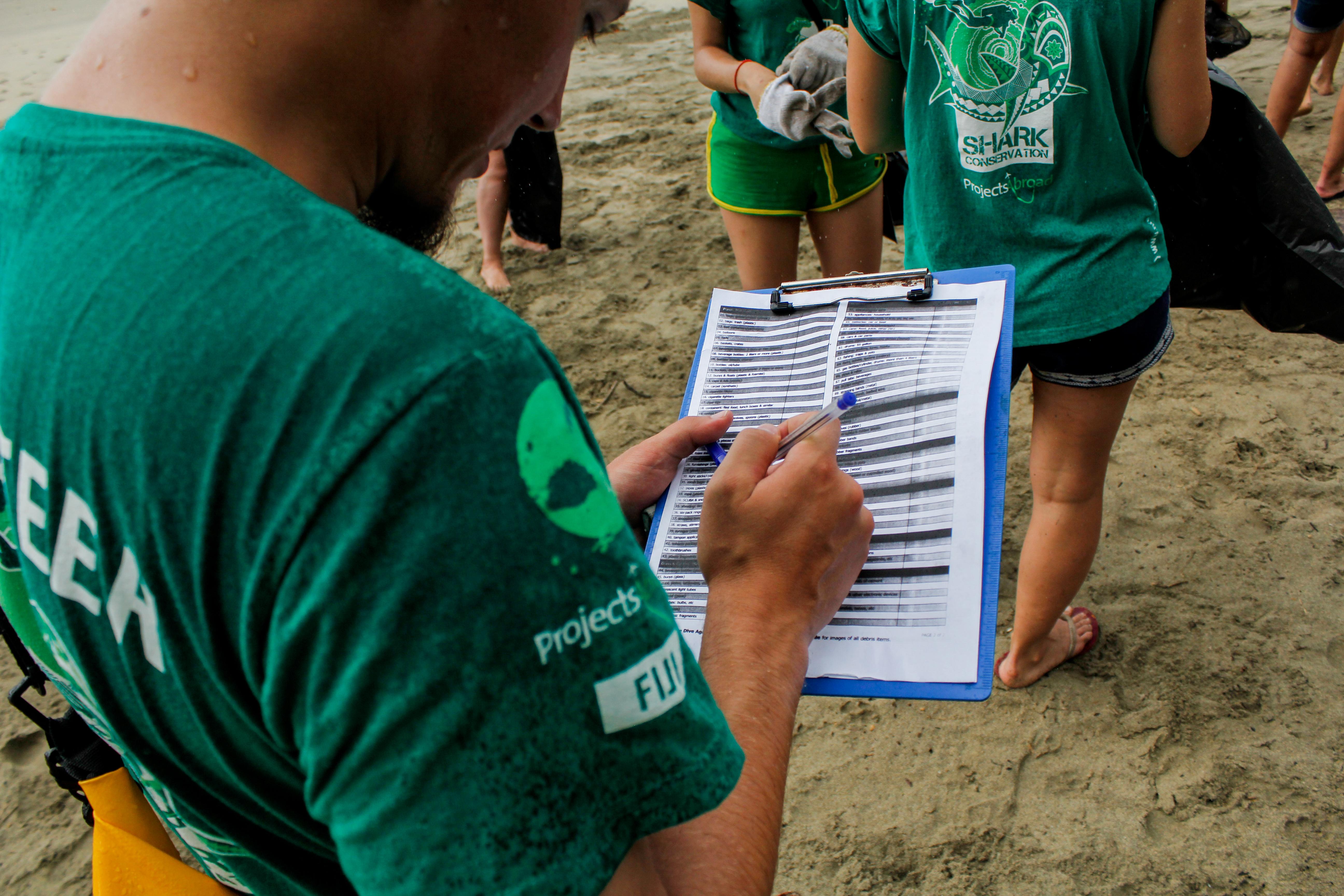 Volunteers from Projects Abroad assist with a beach clean up whilst taking part in shark conservation volunteering work in Fiji. Volunteers from Projects Abroad are seen participating in a beach clean up as part of their shark conservation volunteering work in Fiji.